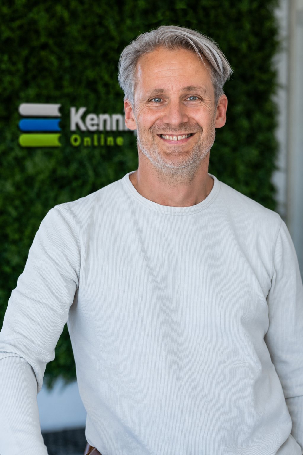 Dorus Stoop, oprichter van Kennisbank Online, voor de groene wand met het Kennisbank Online-logo